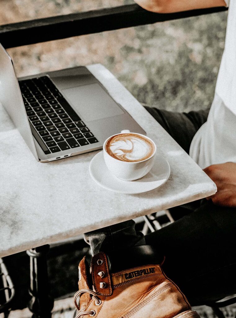 Foto de un hombre sentado con una taza de café y una computadora